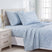 Light blue bedding set with a white floral pattern, including a sheet, two pillowcases, and a folded blanket, styled on a bed in a bright bedroom. #color_classic-meadow-blue