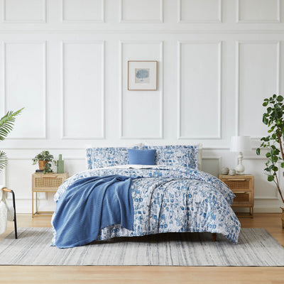 Front view of Rhythm 5-piece duvet cover set showcasing blue abstract print with matching shams and knit throw on a white paneled bedroom
