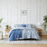 Front view of Rhythm 5-piece duvet cover set showcasing blue abstract print with matching shams and knit throw on a white paneled bedroom