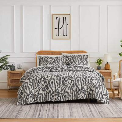 Front view of Khari duvet cover set showcasing slate abstract pattern on a bed with a rattan headboard