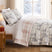 Frosted Pines duvet cover set styled on a bed with ivory winter forest print, pink plaid reverse, matching shams, and Christmas decor.